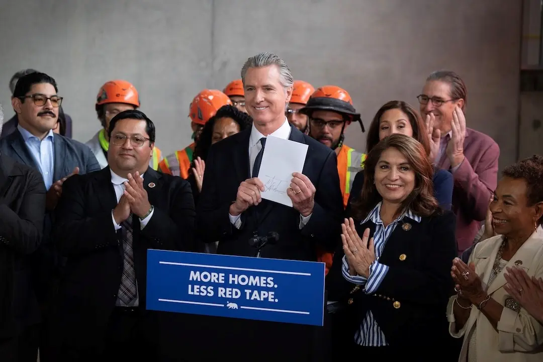 Governor Newsom holding signed legislation before crowd.