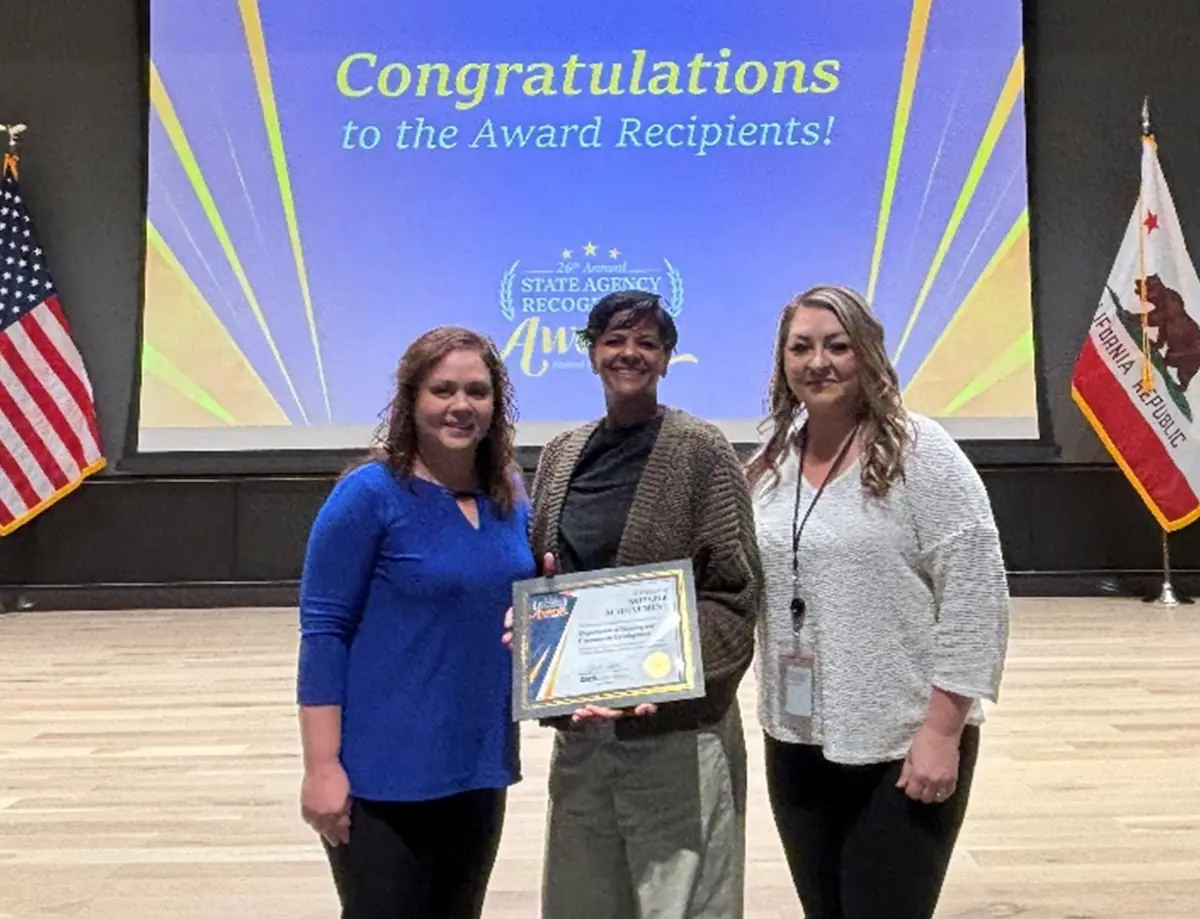 three HCD staff members posing with award