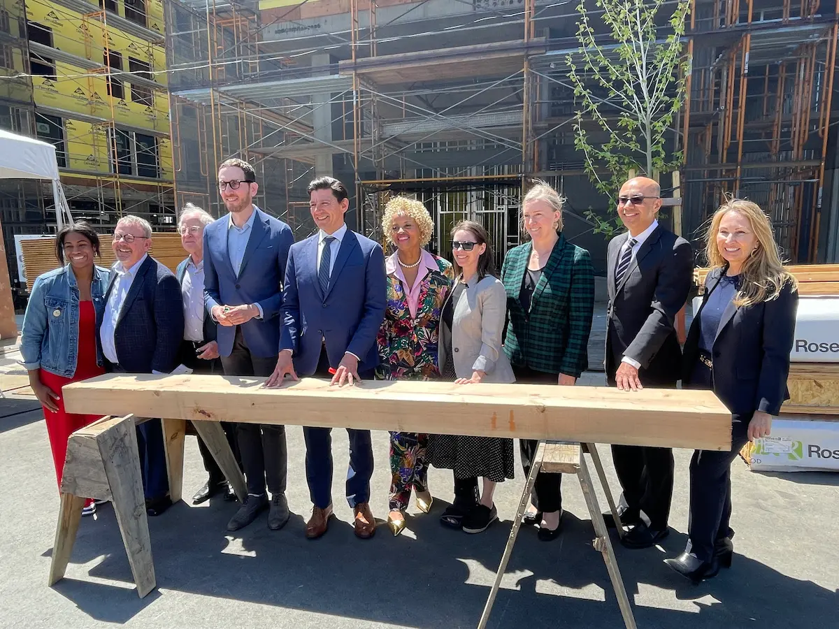 HCD Director Velasquez and other community leaders posing behind ceremonial beam at celebration.